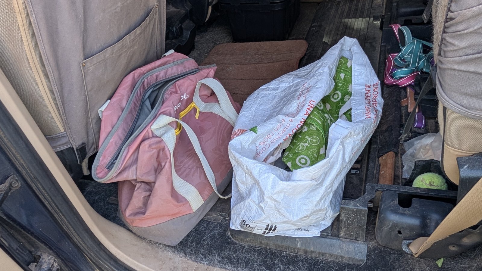 Vehicle lockbox concealed beneath an everyday grocery bag, camouflaged as ordinary clutter inside a car